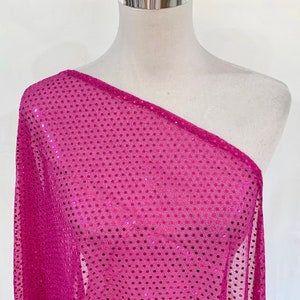 Pode incluir: Um tecido rosa transparente com pequenas lantejoulas. O tecido está drapeado sobre um manequim branco.