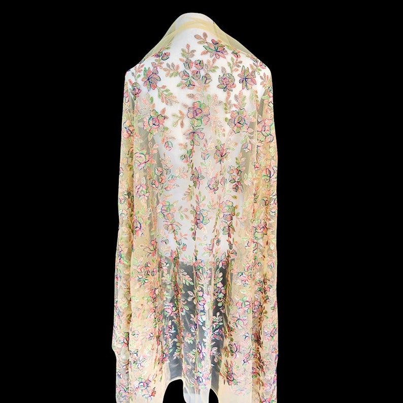 May include: A sheer yellow fabric with a floral pattern in shades of pink, green, and blue. The fabric is delicate and has a soft, flowing texture.