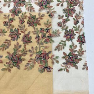 May include: Beige and white fabric with floral embroidery. The embroidery features small, colorful beads and sequins in shades of pink, green, and gold. The fabric is sheer and delicate.