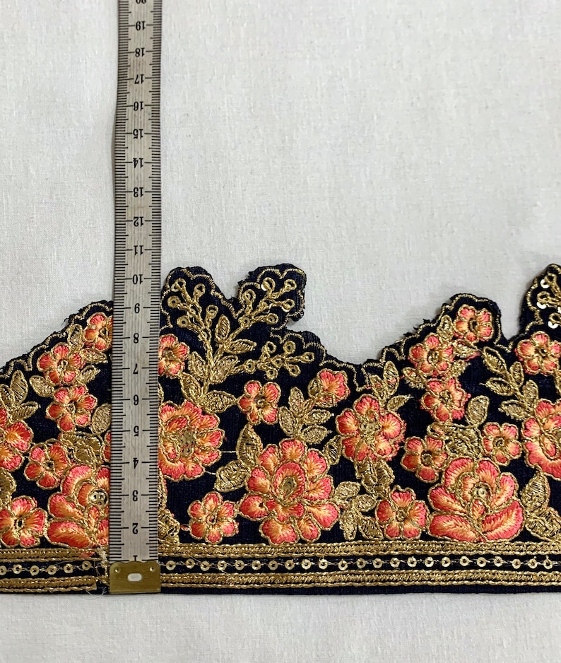 May include: Black velvet trim with gold and peach embroidery. The trim features a scalloped edge and a row of gold sequins.