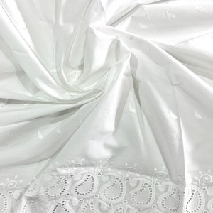 May include: White cotton fabric with a delicate eyelet lace trim featuring a paisley pattern. The fabric is soft and lightweight, perfect for crafting or sewing projects.