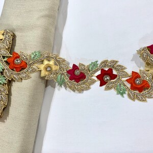 May include: Gold trim lace with red, orange, and green embroidered flowers and leaves. The lace has small clear rhinestones.