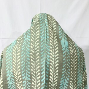 May include: A light gray fabric with a repeating pattern of blue and white teardrop shapes. The fabric has a soft, flowing texture.