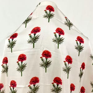 May include: White fabric with a repeating pattern of red carnation flowers with green stems and leaves.