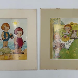 May include: Two framed vintage prints. One shows two children at the beach, one wearing a duck swimsuit. The other shows children having a picnic with a dog. Both are in beige frames.