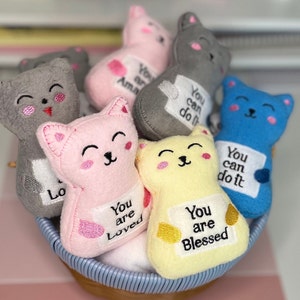 May include: A basket of plush cat toys with embroidered messages. The messages include "You are loved", "You are blessed", and "You can do it".
