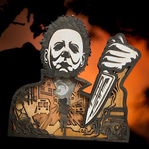 May include: Wooden layered art piece featuring a menacing figure holding a knife, with a Halloween scene backdrop. The artwork is in shades of brown, black, and white, with a pumpkin and a vintage car. The figure's face is white.