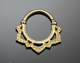 May include: Gold-toned body jewelry with a decorative mandala design. The jewelry is a hoop with a circular shape and a detailed, intricate pattern.