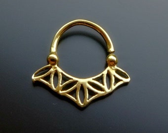 May include: Gold septum ring with a delicate, intricate design. The ring is made of a single piece of metal and has a smooth, polished finish.