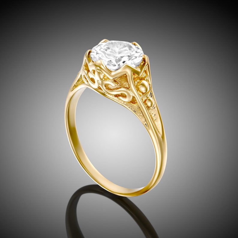 May include: A gold ring with a large, clear, round gemstone set in a detailed, ornate design.
