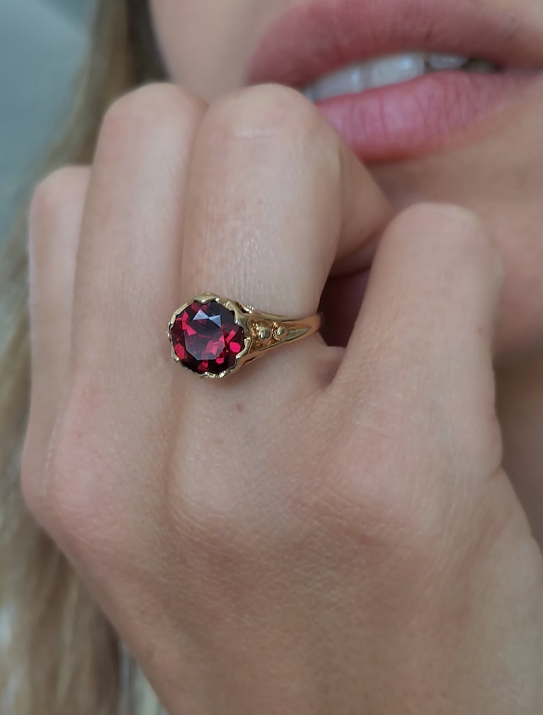 May include: A gold ring with a large, red gemstone set in a detailed, ornate setting.