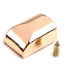 May include: A rose gold metal cap with a small hole in the center and a matching gold screw.