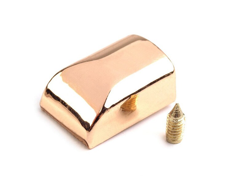 May include: A rose gold metal cap with a small hole in the center and a matching gold screw.