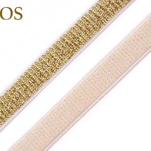 May include: Close-up of two decorative ribbons. One ribbon is gold with a glittery texture, and the other is a light beige color. Both ribbons have a white border. The word "DOS" is in the upper left corner.