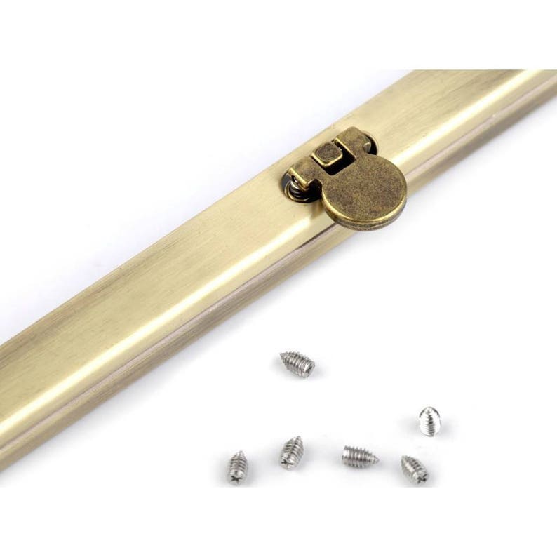 Op de afbeelding: Een goudkleurige metalen sluiting met een ronde, scharnierende sluiting. De sluiting is bevestigd aan een lange, platte metalen strip. De afbeelding toont ook een aantal kleine, zilveren schroeven.