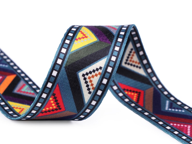May include: A blue, black, red, yellow, and white patterned woven ribbon with a geometric design.