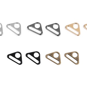 Op de afbeelding: Tien driehoekige metalen schuifgespen in drie verschillende afwerkingen: zilver, zwart en goud.