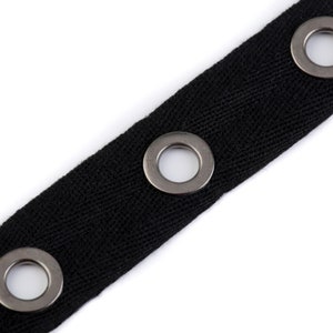 May include: Black fabric trim with silver metal grommets. The trim has three grommets spaced evenly apart.