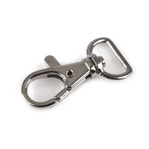 May include: Silver metal swivel clasp with a D-ring. The clasp is designed to attach to a strap or chain.