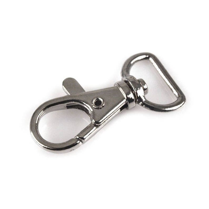 May include: Silver metal swivel clasp with a D-ring. The clasp is designed to attach to a strap or chain.