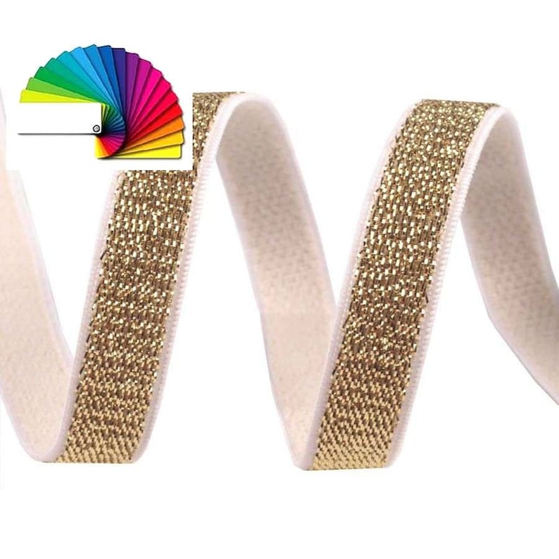 May include: Cream-colored velvet ribbon with a gold metallic border. The ribbon is curled and has a color palette fan in the upper left corner. The ribbon is likely used for crafting, sewing, or gift wrapping.