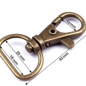 May include: A gold-toned metal swivel clasp with a D-ring. The clasp measures 42 mm long, 10 mm wide, and the D-ring measures 20 mm long and 18 mm wide.