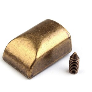 May include: A gold-toned metal furniture leg cap with a rounded top and a screw for attaching it to a piece of furniture.