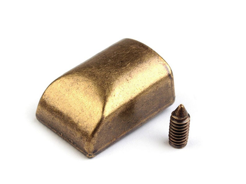 May include: A gold-toned metal furniture leg cap with a rounded top and a screw for attaching it to a piece of furniture.