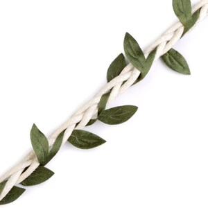 May include: A white braided rope with green fabric leaves attached. The rope is twisted and the leaves are evenly spaced.