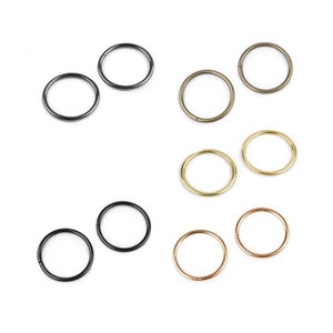 Op de afbeelding: Assortiment van tien springringen in verschillende afwerkingen, waaronder zwart, goud en zilver. De springringen zijn allemaal even groot en zijn gerangschikt in twee rijen van vijf.