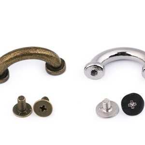 May include: Two sets of metal D-ring handles with screws. One set is antique brass and the other is silver. Each set includes two screws and a washer.
