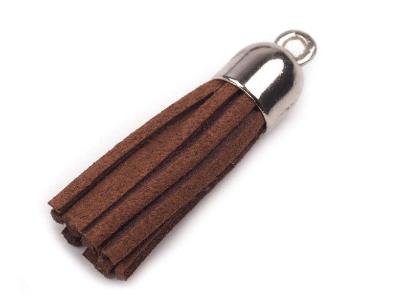 May include: A brown suede tassel with a silver metal top and a loop for attaching to a key chain or other item.