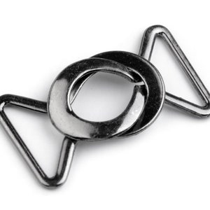 May include: A silver metal slider buckle with two triangular loops. The buckle is designed to be used for adjusting the length of straps or belts.