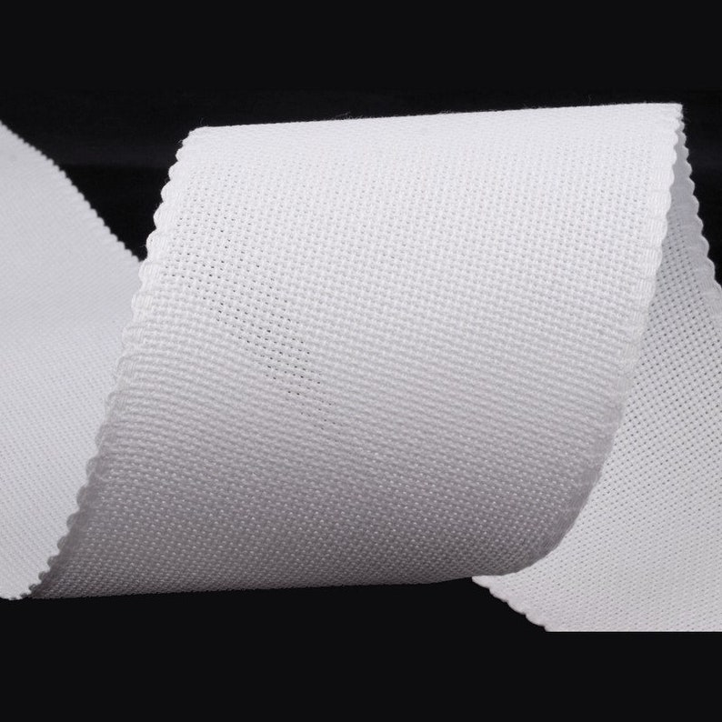 Puede incluir: Cinta de algod&oacute;n blanco, un tejido tejido con una textura lisa. La cinta est&aacute; enrollada y muestra el tejido de la tela.