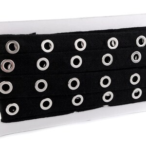May include: Black cotton ribbon with silver grommets. The ribbon is wound on a white cardboard spool.