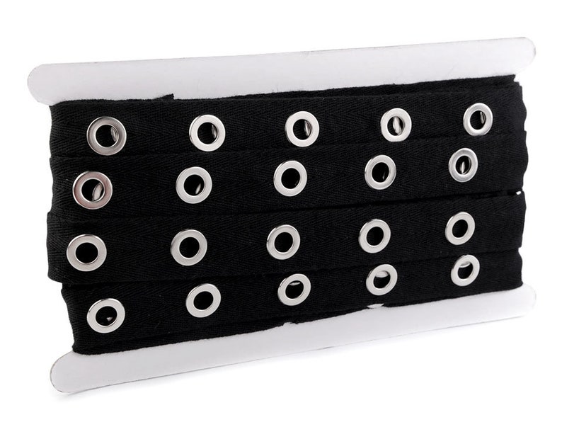May include: Black cotton ribbon with silver grommets. The ribbon is wound on a white cardboard spool.