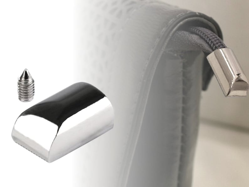 May include: A silver metal zipper pull with a pointed end and a rounded base. The zipper pull is attached to a gray zipper.