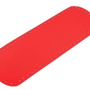 May include: Red leather craft piece with holes around the edges. This piece is used for making bags and other leather goods.