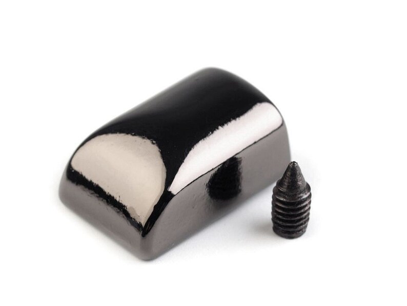 May include: A black metal furniture leg cap with a rounded top and a screw. The cap has a shiny, polished finish.