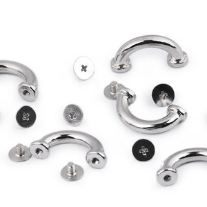 May include: A set of five silver metal D-ring hardware pieces with screws. The D-rings are curved and have a smooth finish. The screws are silver and have a cross-shaped head.