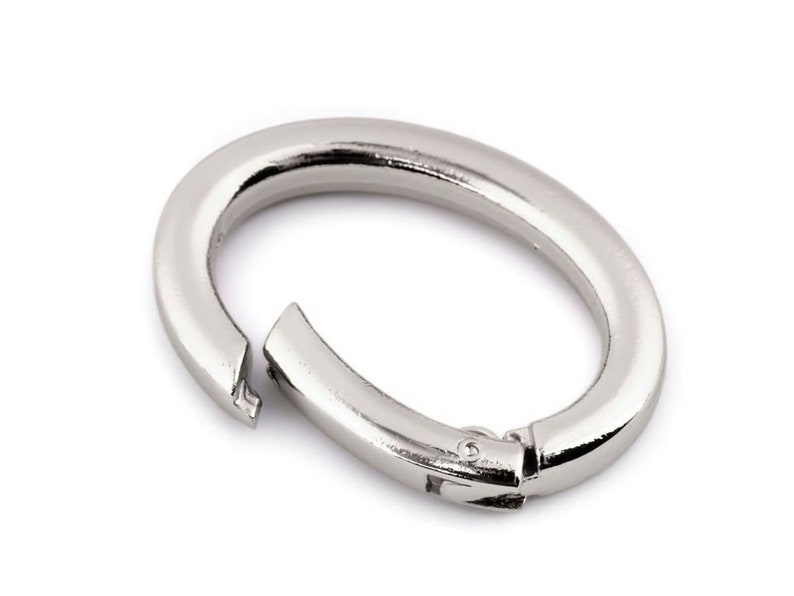 May include: Silver oval-shaped ring with a spring-loaded clasp.