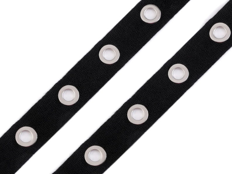 May include: Black ribbon trim with silver grommets. The ribbon is approximately 1 inch wide and has a herringbone weave.
