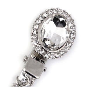 May include: A silver-toned clasp with a large clear crystal surrounded by smaller crystals.