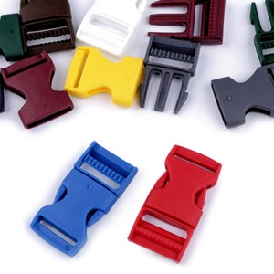 Op de afbeelding: Assortiment van kleurrijke plastic gespen in blauw, rood, geel, groen en bruin. Deze duurzame gespen zijn ontworpen voor riemen en sluitingen, geschikt voor diverse projecten.