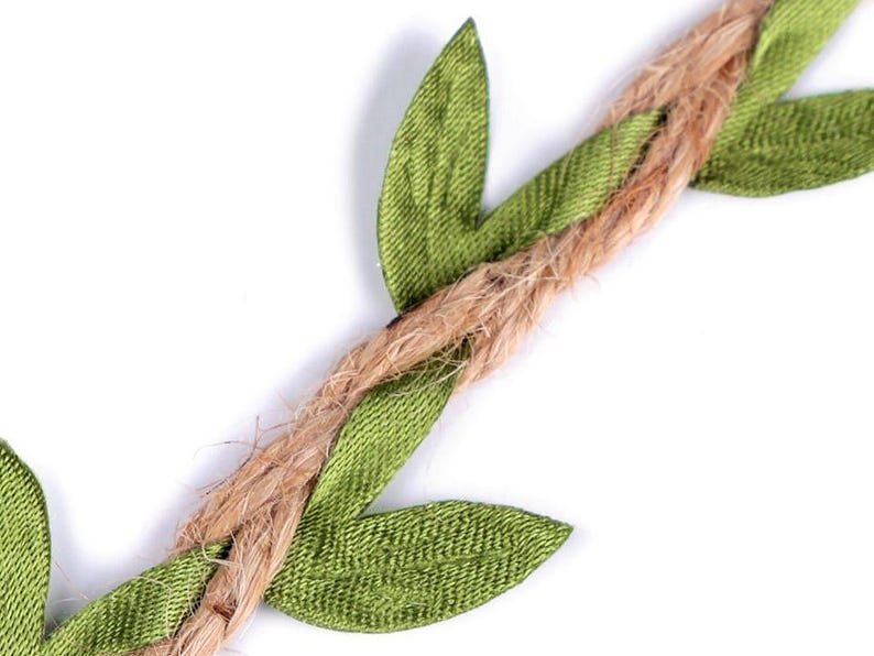 May include: A close-up of a brown jute twine garland with green fabric leaves. The leaves are sewn onto the twine and are arranged in a repeating pattern.