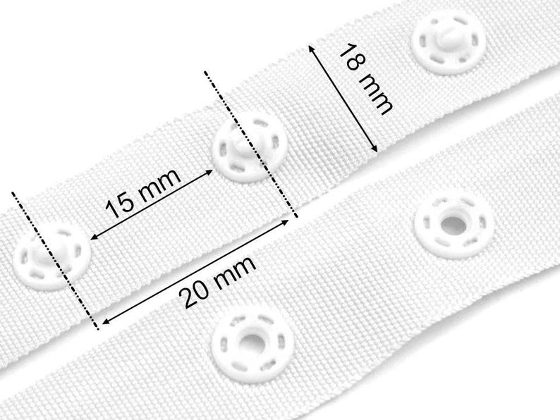 Puede incluir: Cinta blanca con corchetes con cuatro corchetes de pl&aacute;stico blanco. La cinta mide 18 mm de ancho y los corchetes tienen un di&aacute;metro de 15 mm. La distancia entre los corchetes es de 20 mm.