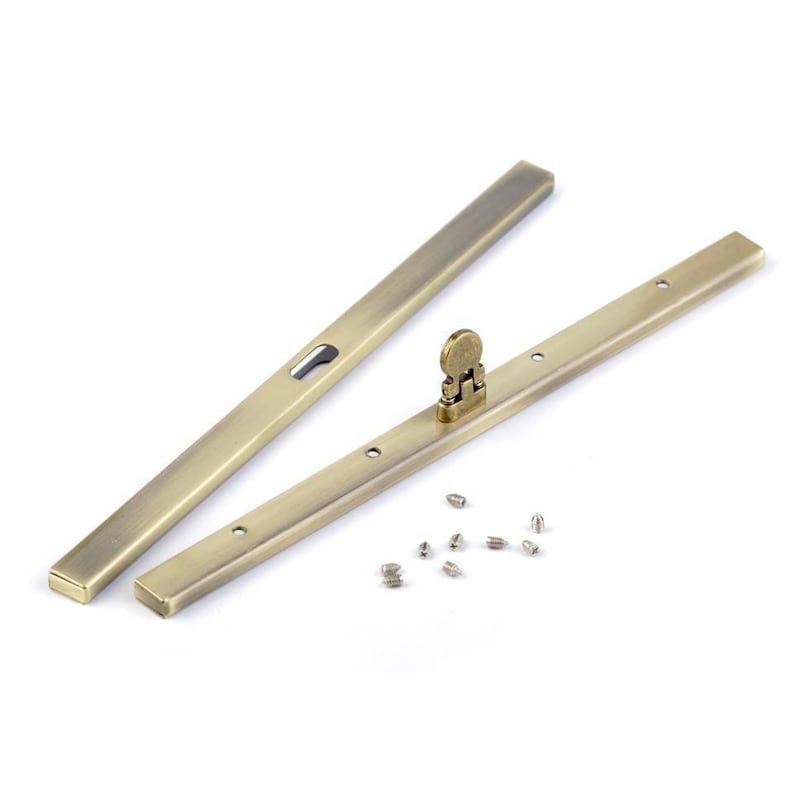 Op de afbeelding: Twee antieke gouden metalen schuifdeurbeslag met een klein metalen slot en een set schroeven.