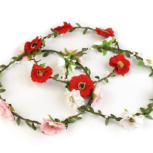 May include: A floral crown featuring red, white and pink flowers with green leaves. The crown is made from artificial flowers and is designed to be worn on the head.