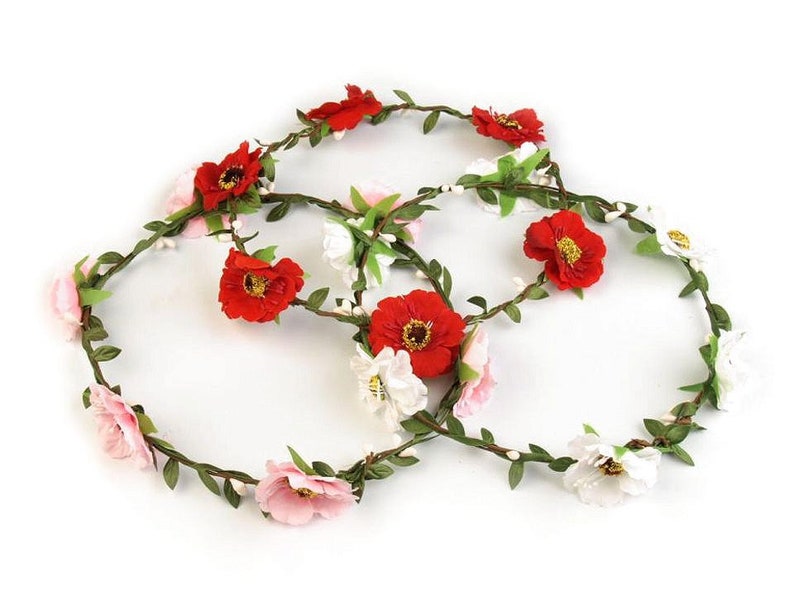 May include: A floral crown featuring red, white and pink flowers with green leaves. The crown is made from artificial flowers and is designed to be worn on the head.