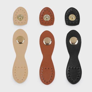 Op de afbeelding: Een verzameling van zes leren drukkers in beige, bruin en zwart. Elke sluiting heeft een metalen drukker en decoratieve stiksels of perforaties. De vormen zijn ovaal en langwerpig, geschikt voor knutselprojecten. Afmetingen in centimeters.